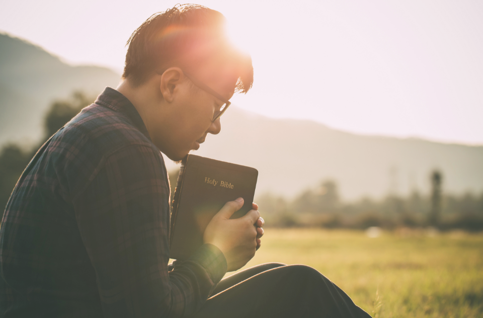 Person praying and reflecting with a journal while seeking emotional healing.